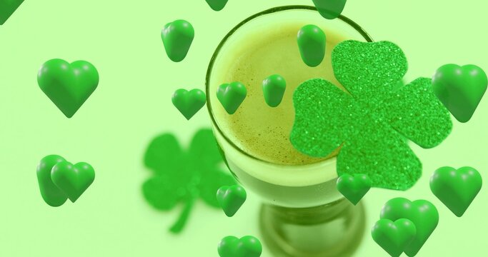 Showing stemmed glass holding layered green drink with crema in studio, glitter clover and hearts