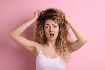 Fototapeta premium Unhappy woman with tangled hair on pink background