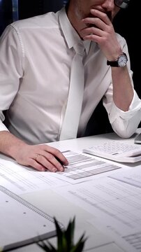 Business professional working late on financial audit in modern office, analyzing tax documents and managing paperwork deadlines with precision and expertise