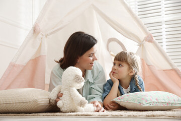 Mother and her daughter with toy near wigwam at home © New Africa