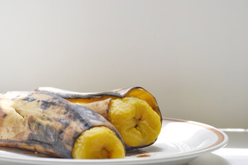 A close-up of two perfectly cooked ripe bananas served on a clean white plate. Ideal for food, tropical cuisine, healthy snack, breakfast, or dessert concepts. Bright and appetizing presentation, perf © Nret