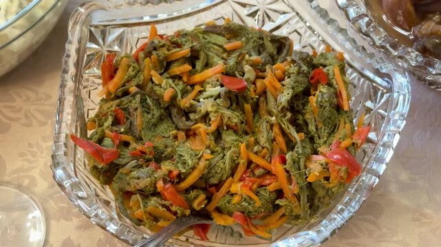 A glass cup with bracken fern salad with spices stands on a beautiful background.