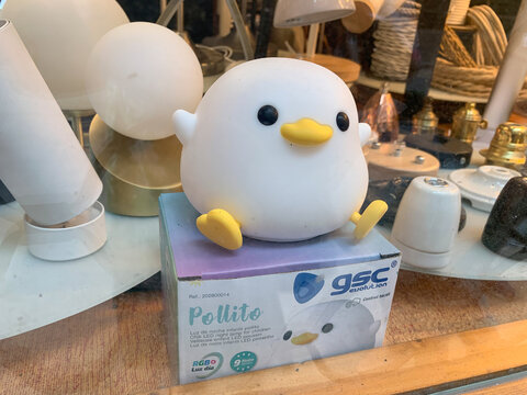 Reus, Spain - August 03, 2025: Cute chick shaped LED night light lamp Pollito by gsc evolution displayed in a shop window with decorative lamps and home lighting products