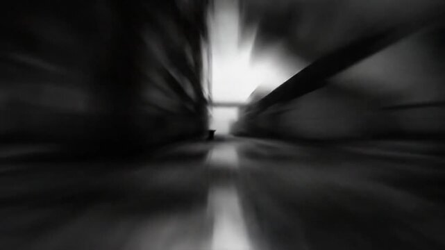 Black and white shot of an abandoned industrial area with buildings, puddle reflections, and bright sunlight