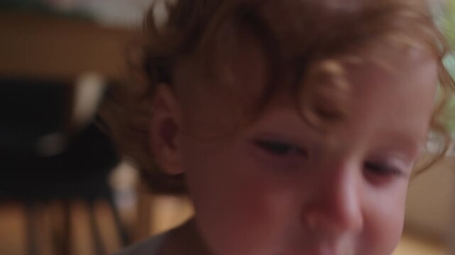 Toddler standing beside table after bumping head and holding it with hand, capturing minor accident, reaction, and candid everyday childhood moment in home environment