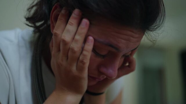 Woman sitting with head in hands showing fatigue and emotional overwhelm close up moment of stress exhaustion and mental load during everyday life at home