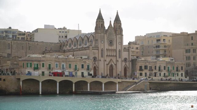 Neo-gothic architecture of the Carmelite Balluta Parish Church under a cloudy overcast sky, Malta.