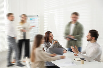 Fototapeta premium Colleagues working indoors, motion blur effect. Hustle and bustle office life