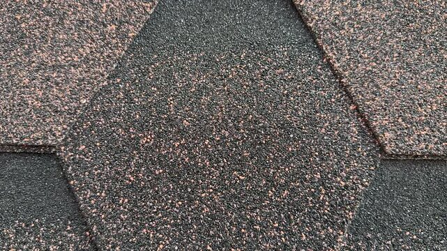 Close-up hexagonal asphalt shingle texture, brown and gray mineral granules, overlapping hexagonal pattern on sloped roof.