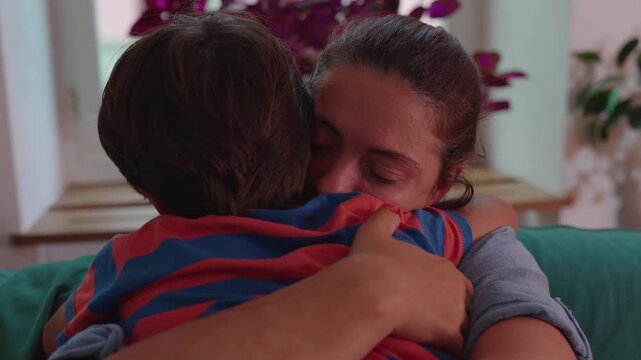 Mother embracing child on sofa with eyes closed intimate moment of comfort love and emotional connection during quiet family time at home