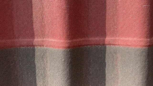 Red gray corrugated ondulin tile closeup showing textured waves, sunlight casting striped shadows, visible fastener detail.