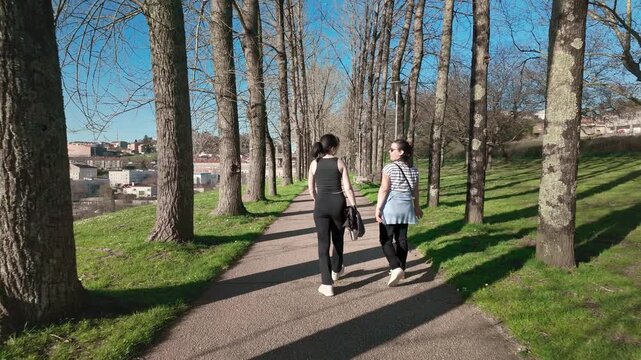Mother and daughter walking and hugging on a beautiful tree lined path in Santiago de Compostela, enjoying a moment of connection, mindfulness, and healthy living in a serene natural setting