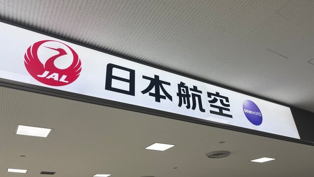 Japan Airlines JAL logo and Nihon Koku branding with oneworld alliance logo on airport terminal signage at Narita International Airport - Chiba, Japan, October 29, 2025