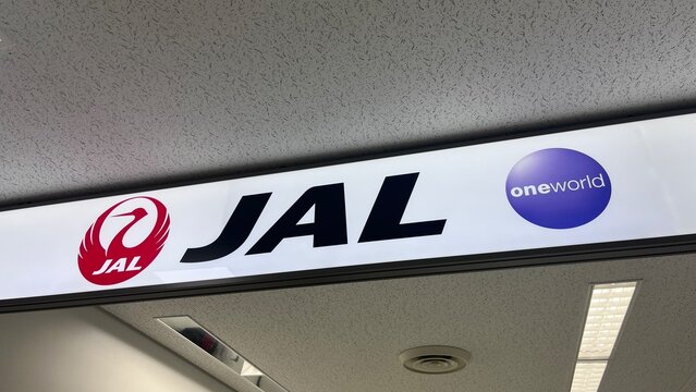 Japan Airlines JAL logo signage with Oneworld alliance branding at Narita International Airport check-in terminal facilities - Chiba, Japan, October 29, 2025