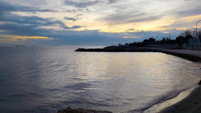 Peaceful View of Sarkoy Beach and Coastline at Early Morning with Golden Sunlight Reflecting on Calm Waters, Stone Breakwaters and Ships on the Horizon, Tekirdag, Turkey.