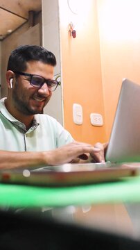 Portrait of a young Hispanic man working on a laptop at a desk in his home in Bosa, Bogot&aacute;, Colombia. Concept of remote work and happiness