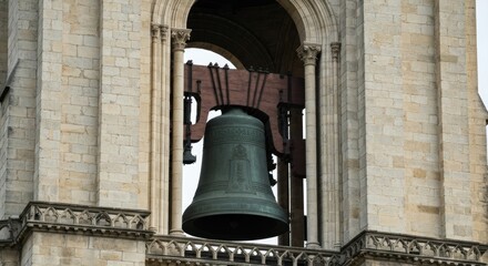 Obraz premium Large bronze bell suspended in a stone tower's arched opening