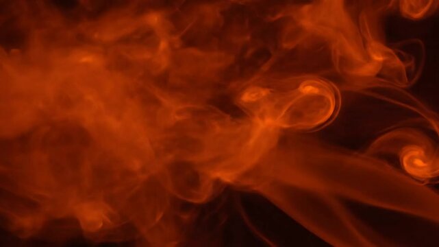 Abstract flowing orange smoke on a dark background showing swirling textures and patterns in motion