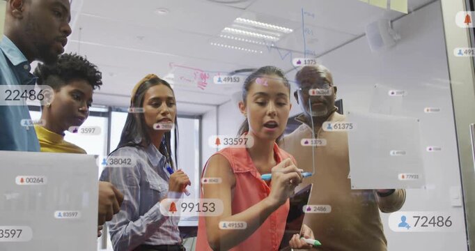 Vertical video: Lead woman tapping glass with marker, drawing biz plan while UI numbers on glass