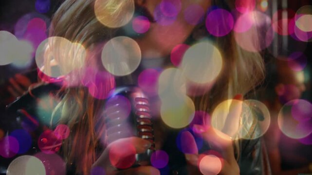 Camera pulling back, singer gripping microphone and performing song as pulsing bokeh revealing face