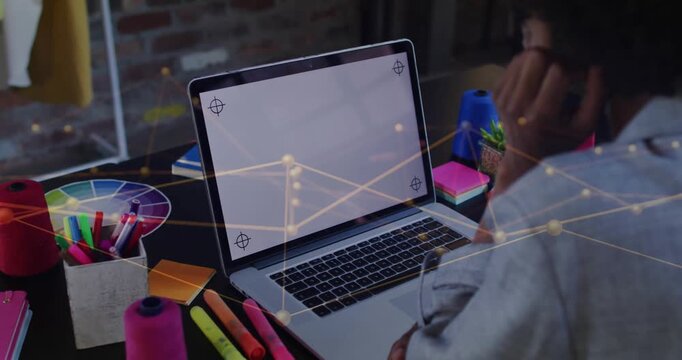Designer leaning to laptop adjusting glasses as network overlay shifting, mapping design data links