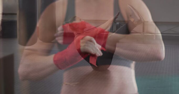 Grabbing red wrap woman in black sports bra winding tightening hands in gym, preparing for boxing