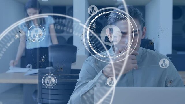 Male worker at laptop while female admin sorting papers, HUD overlay growing mapping business data