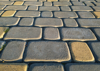 The texture of dark gray granite paving stones in the light of the setting sun. Natural block stone background.