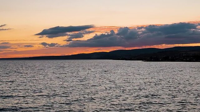 Scenic Sunset View of the Marmara Sea with Silhouette of Wind Turbines on the Hills, Dramatic Orange Sky and Dark Clouds over the Coastline of Sarkoy, Turkey.