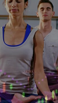 Vertical video: Woman meditating in studio, camera panning up causing health charts tracking breath