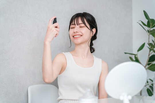 Asian women using spray toner for skincare.