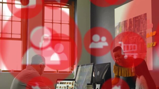 3 colleagues leaning over monitors, presenter showing phone, starting design review with red icons