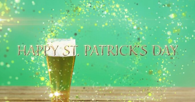 Showing green beer pint with foam sitting on wooden tabletop, gold HAPPY ST