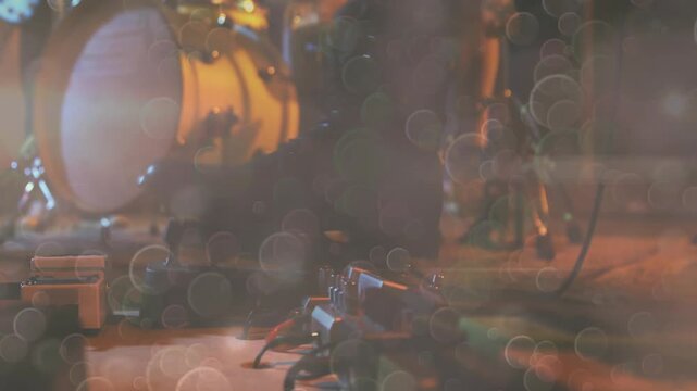 Showing bass drum with white drumhead and golden shell, pedalboard glowing at small stage corner