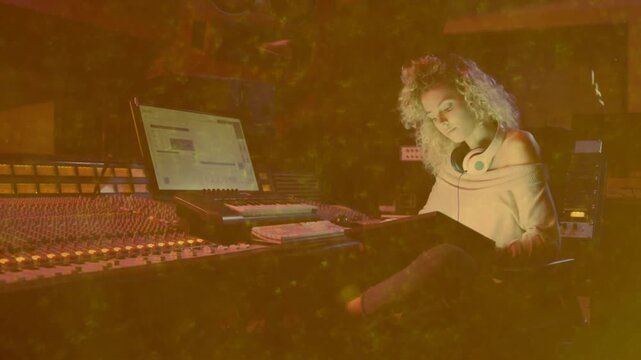 Woman producing at mixing console starting checking notebook, adjusting hair, moving faders for mix