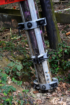 Galvanized iron pole splint, reinforcing metal with collar clamps on old wooden train trestle structural support beams, maintenance and repair patch for added stability and safety
