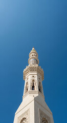 Obraz premium A close-up, low-angle view of a beautifully detailed minaret against a clear, vibrant blue sky, showcasing Islamic architecture.