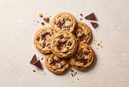 Top down view of a pile of fresh baked chocolate chip cookies with chocolate chunks and crumbs