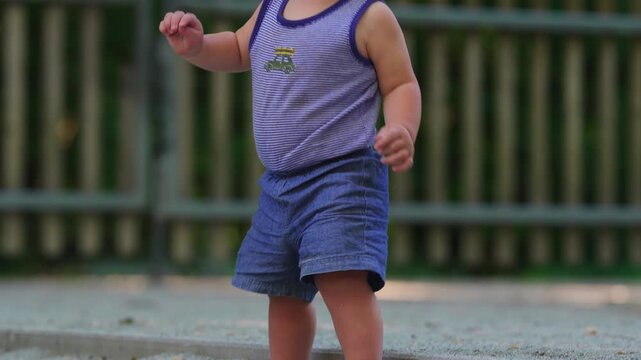 Toddler standing in playground sand while regaining balance after small wobble, early childhood moment showing determination coordination and learning to stabilize body
