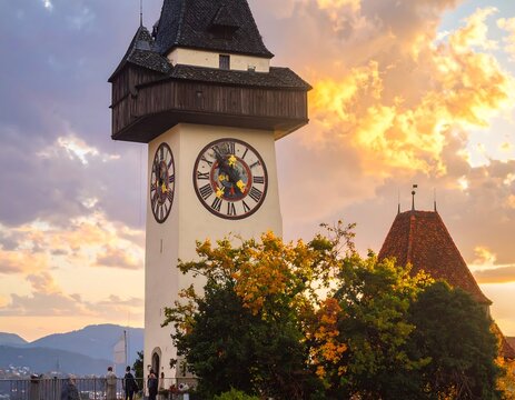 A clock tower amidst trees and a cloudy sky at sunset