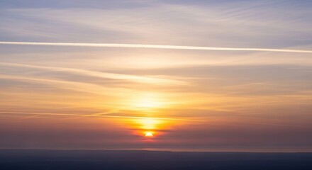 Obraz premium A breathtaking sunset with a vibrant orange sky and a setting sun, casting a warm glow over the horizon. The clouds are a mix of warm hues, creating a stunning visual display.