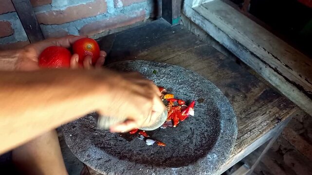 High-quality footage of a housewife grinding sambal in a mortar, showcasing traditional Indonesian cooking, rich texture, and authentic homemade flavors.