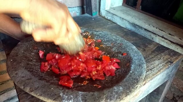 High-quality footage of a housewife grinding sambal in a mortar, showcasing traditional Indonesian cooking, rich texture, and authentic homemade flavors.