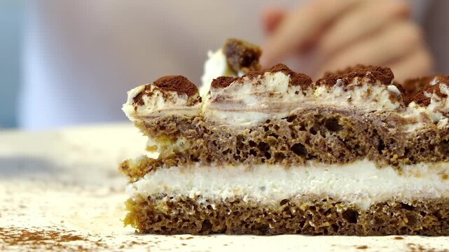 Delicious tiramisu cake slice being eaten with a spoon, close up sweet dessert.