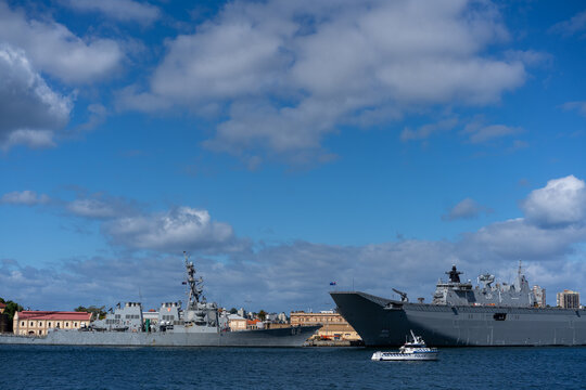 Naval warships docked at military port with police boat in harbor under blue sky with clouds in