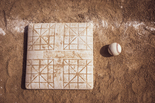 Baseball and base on dirt sports field
