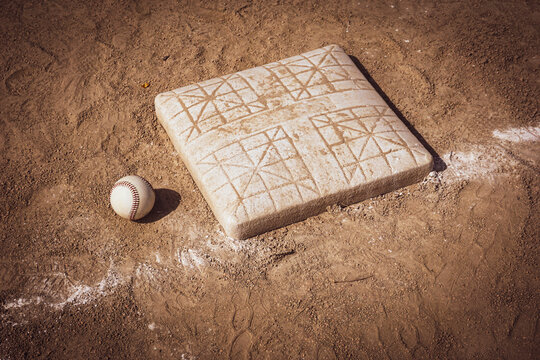 Baseball and base on dirt sports field