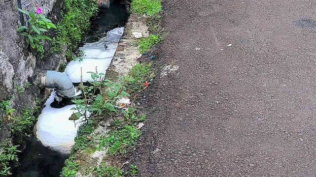 Foamy Wastewater Flowing From Roadside Drain Pipe Causing Urban Pollution And Water Contamination.