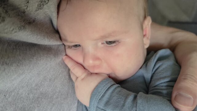 Young baby sucking on his thumb while being held 4k
