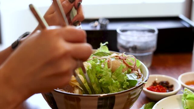 Asian Person Eating Vietnamese Noodle Salad With Chopsticks and Spoon